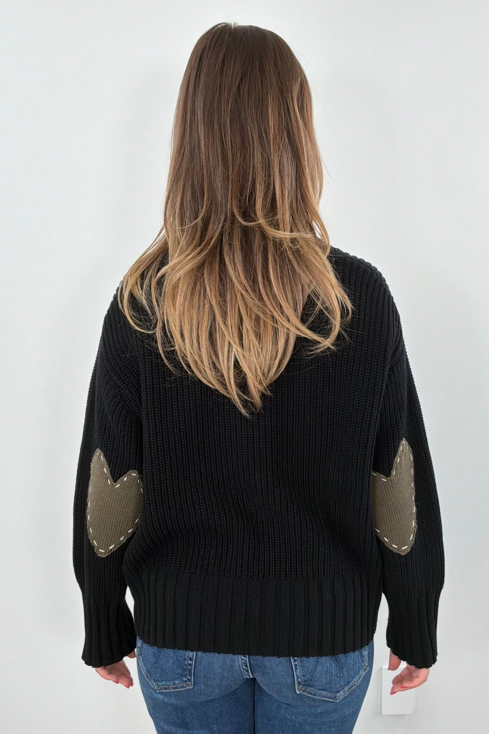 Woman wearing a black sweater with green heart patches