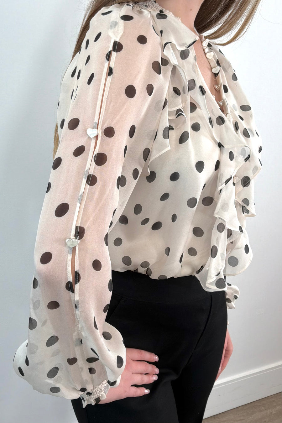 Close-up of a sheer ruffle blouse with polka dots tucked in