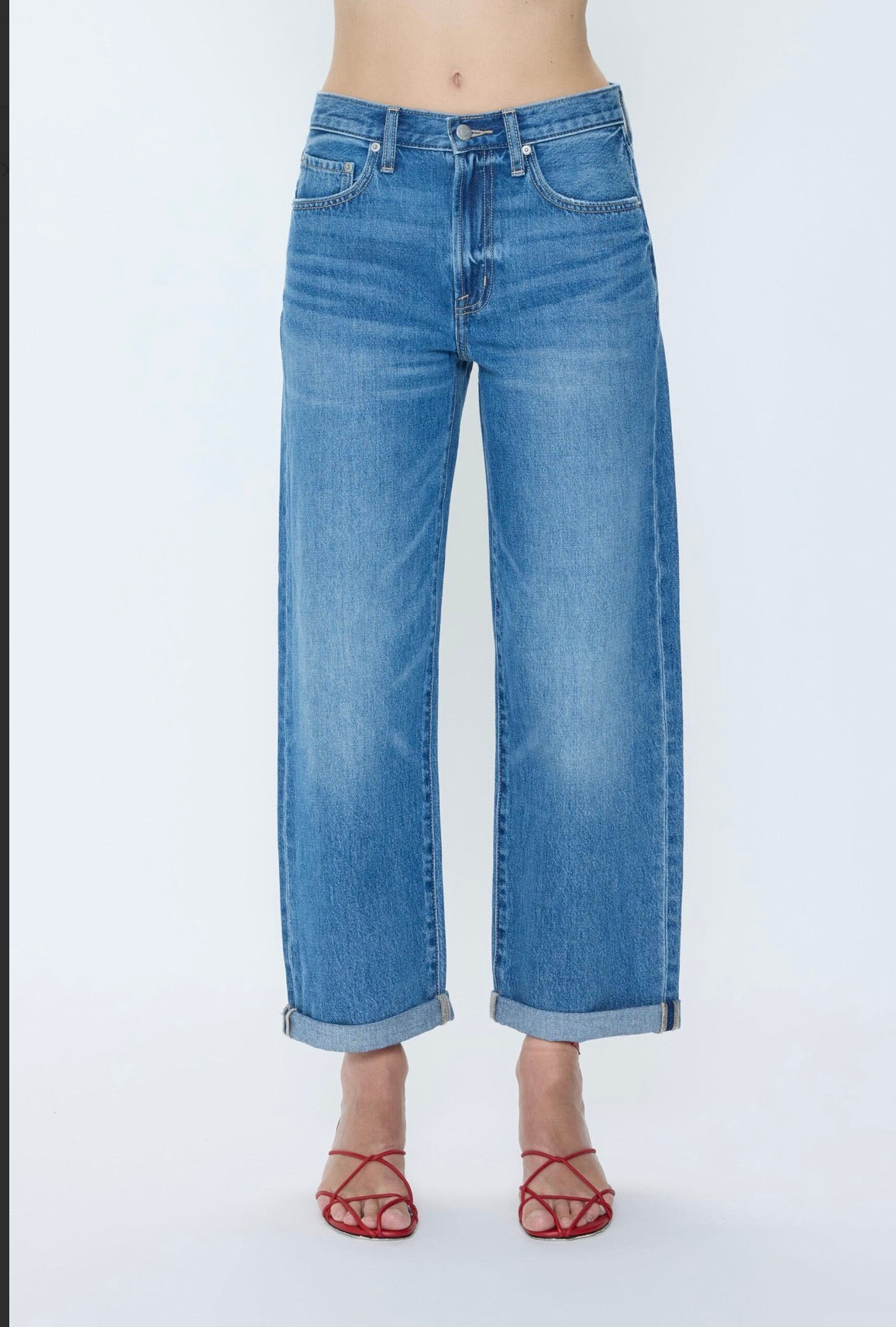 Close up of Woman wearing a mid washed blue wide leg rolled hem pair of jeans