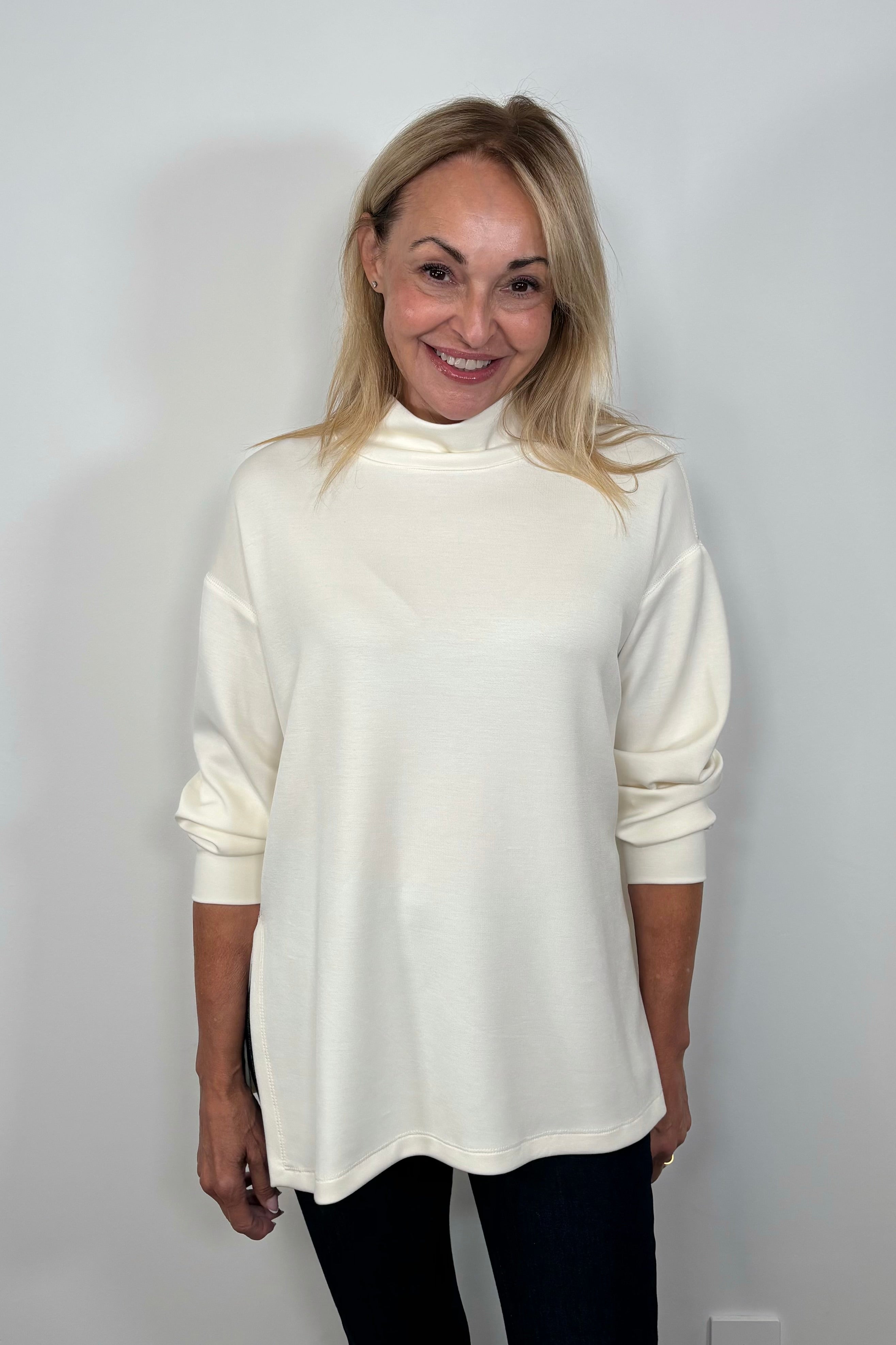 Front facing woman wearing a white boxy turtleneck top