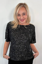 Woman wearing an oversized black sequin top 