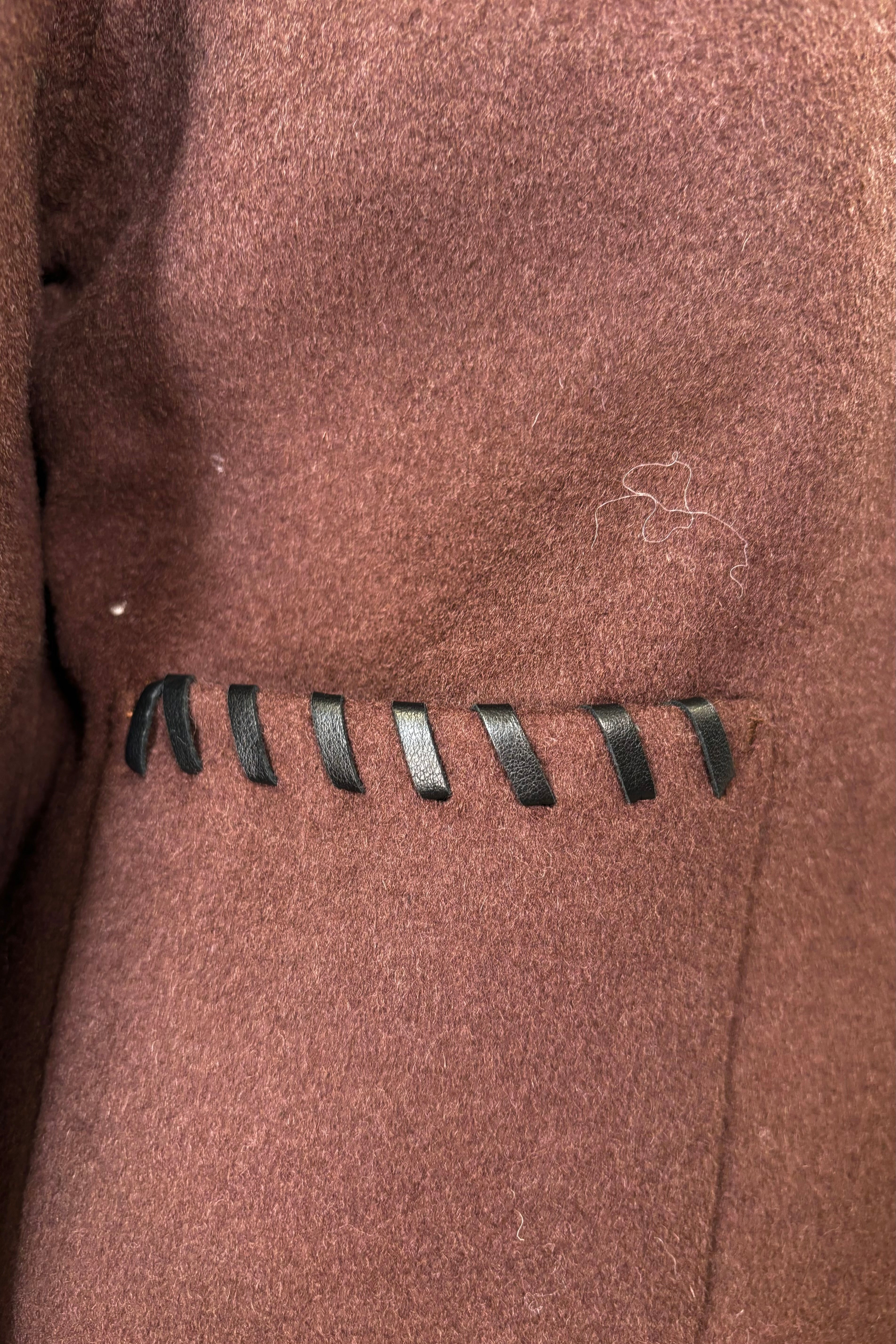 Close up of brown wool coat’t pocket with whipstitch detailing