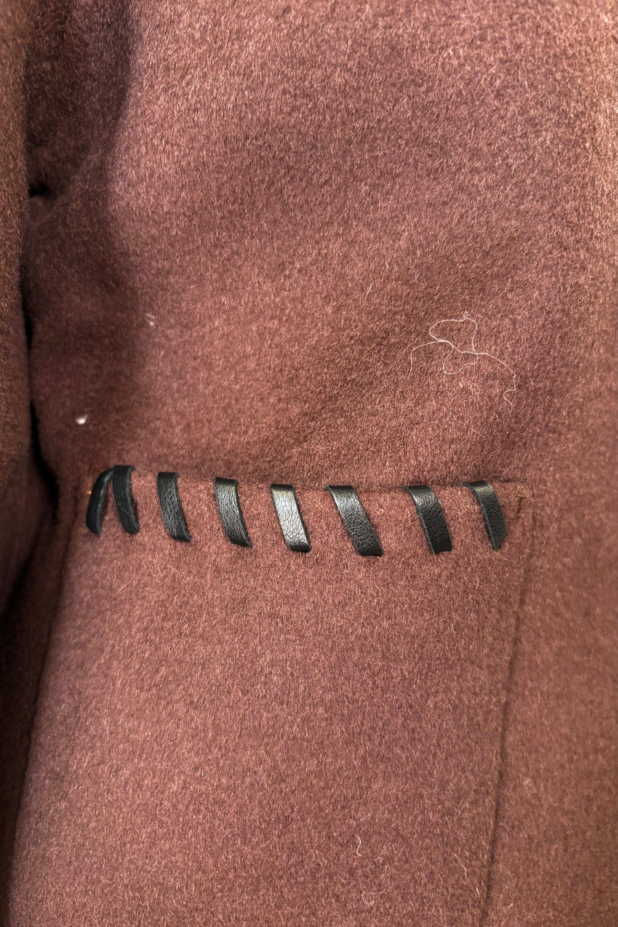 Close up of brown wool coat’t pocket with whipstitch detailing