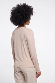 Woman wearing a beige long-sleeve crew neck top. 