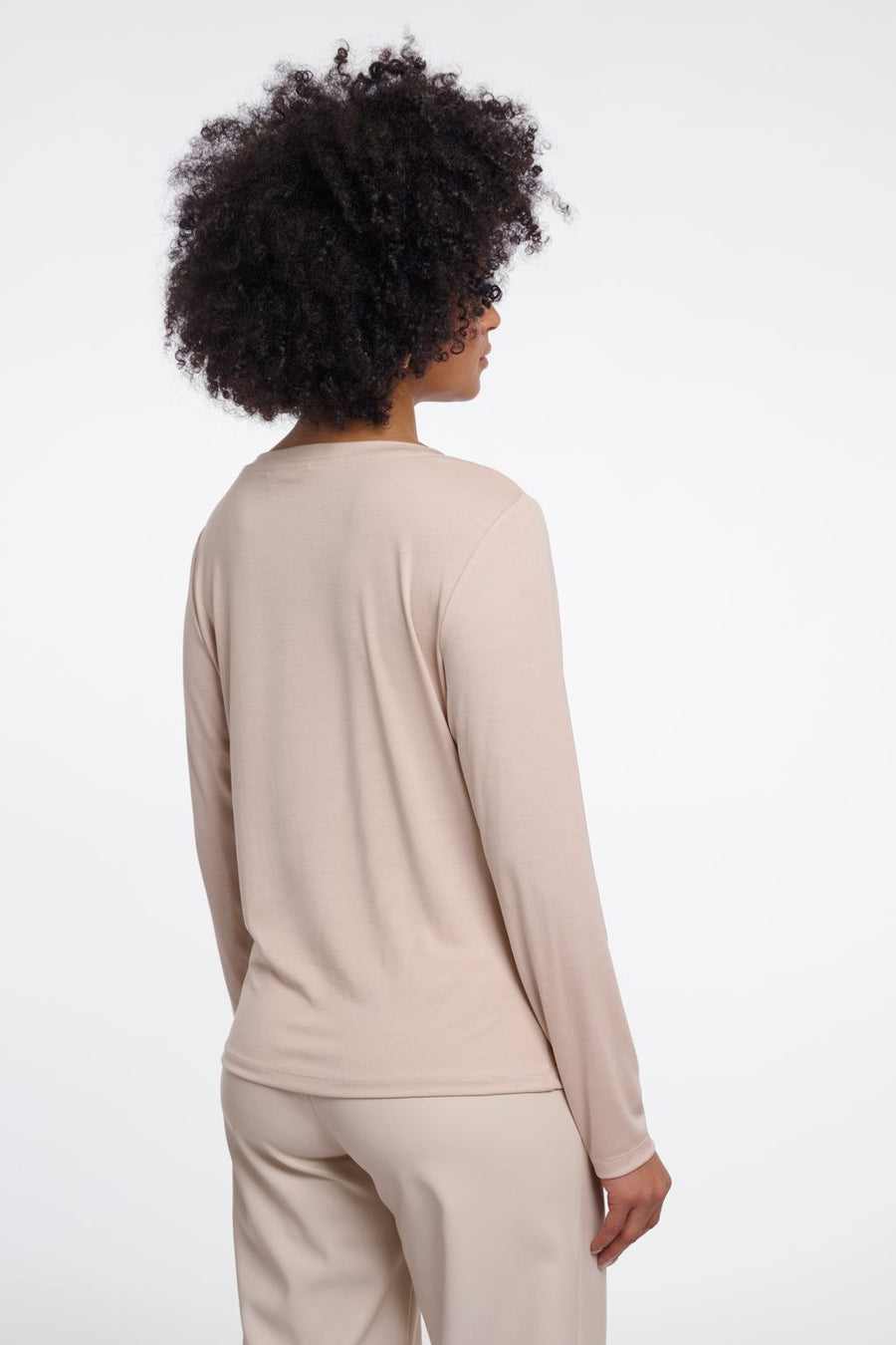 Woman wearing a beige long-sleeve crew neck top. 