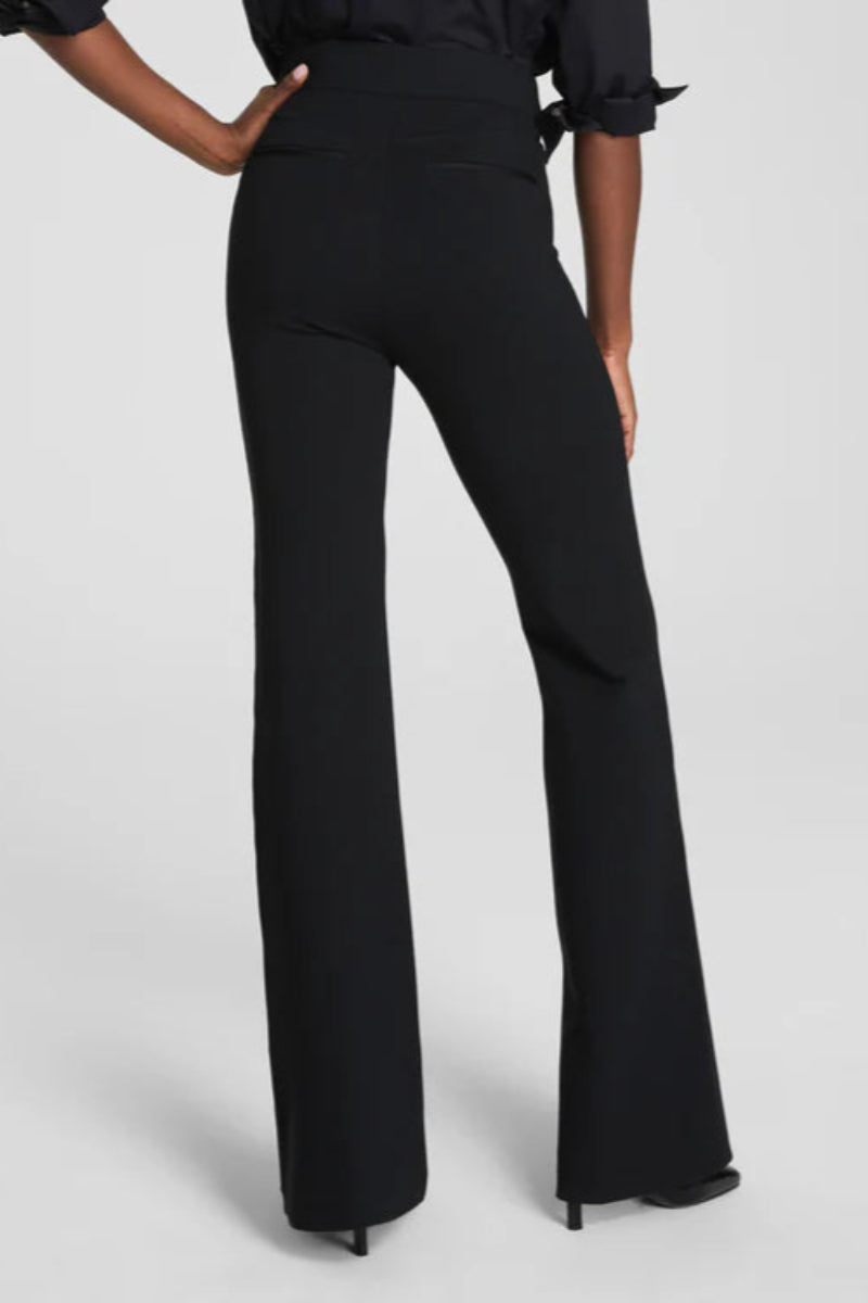 Black flared pants worn by a person on a light gray background