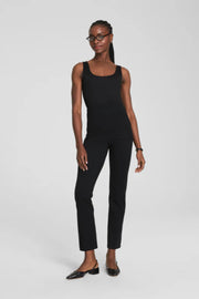 Woman wearing a black sleeveless top and black slim pants on a white background