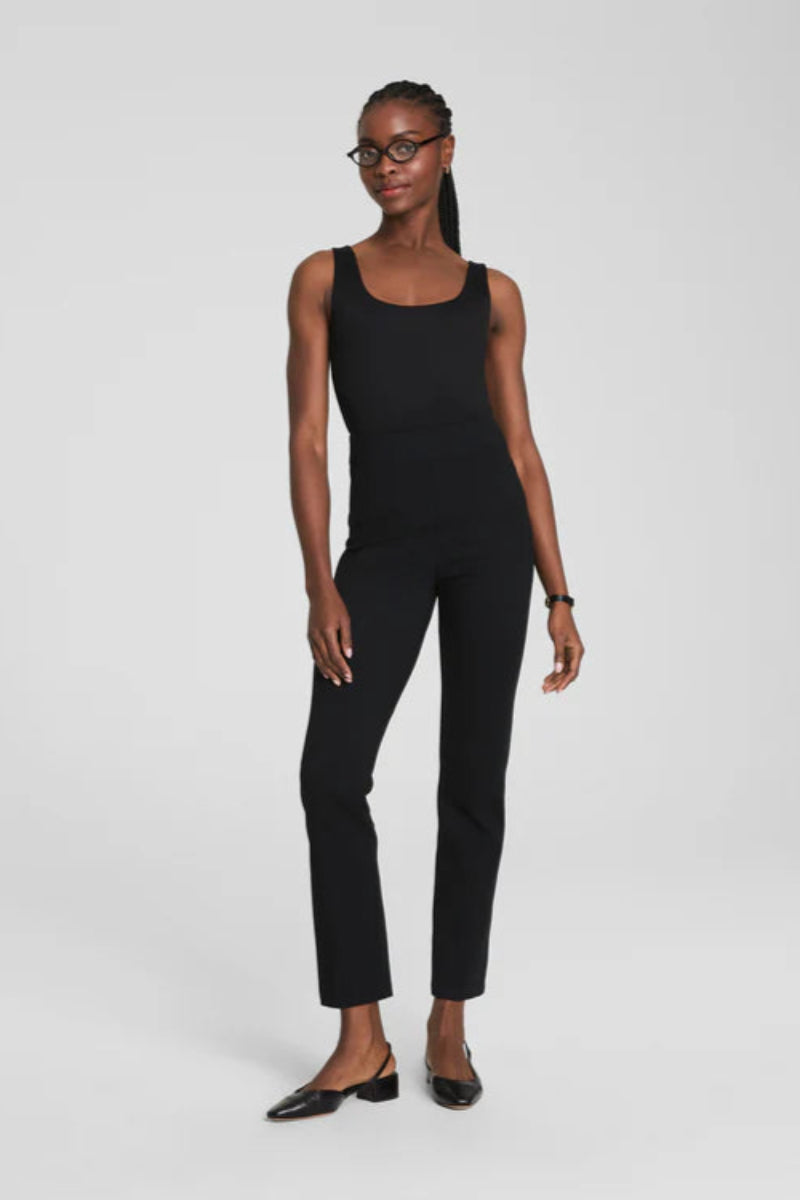 Woman wearing a black sleeveless top and black slim pants on a white background