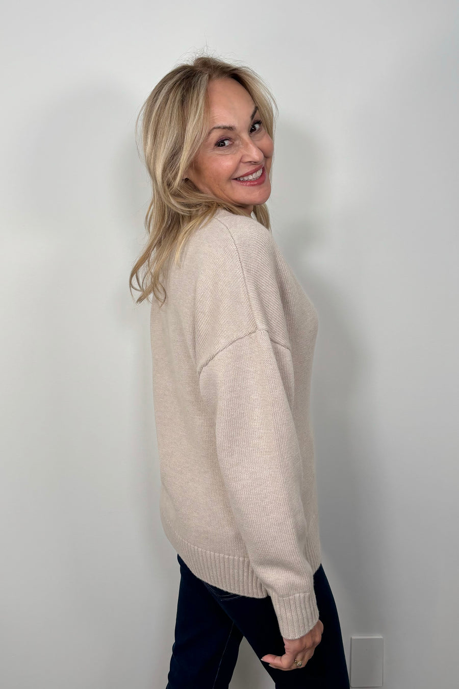 side view of a woman wearing a fitted 3 button beige knitted cardigan