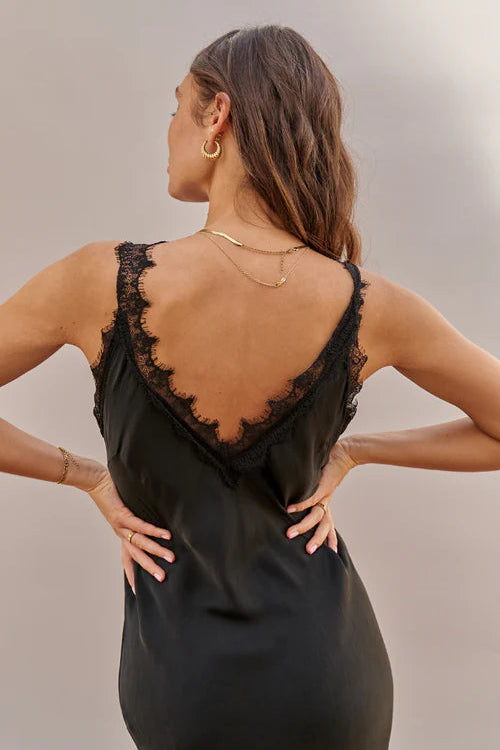 Woman wearing a black dress with lace detailing on a neutral background