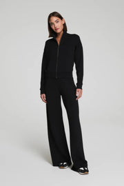 Woman wearing a black track outfit on a plain background