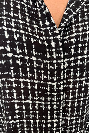 Close-up of the  neckline of a black and white grid patterned blouse