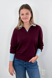 Woman wearing a burgundy sweater with a blue collar