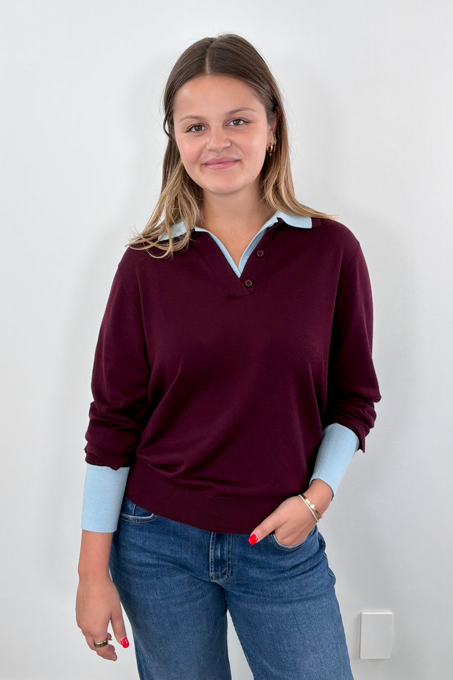 Woman wearing a burgundy sweater with a blue collar