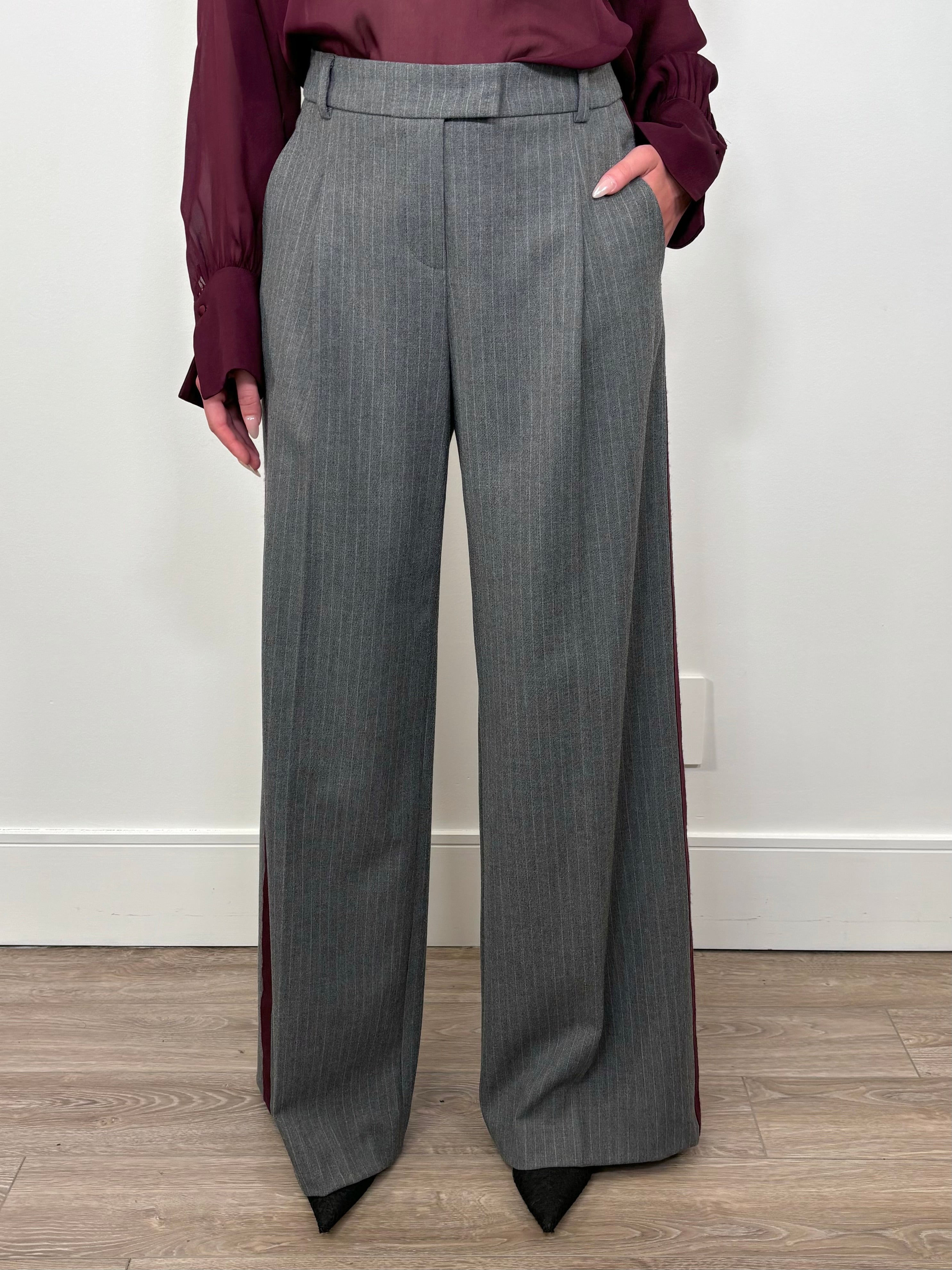 Front view of woman wearing a gray pinstripe wide leg pant with a burgundy line down the leg