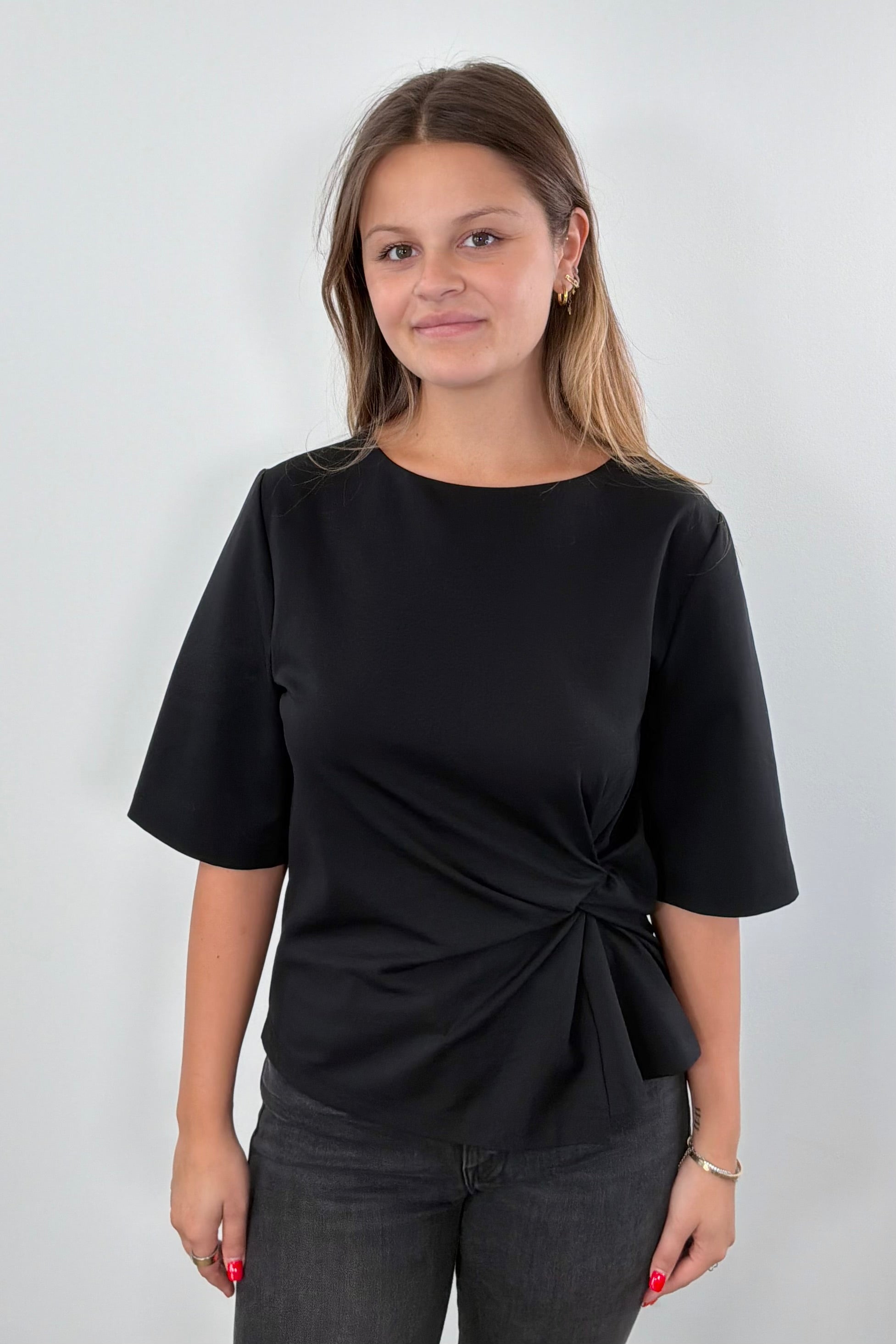 Woman wearing a black top with a knot detail