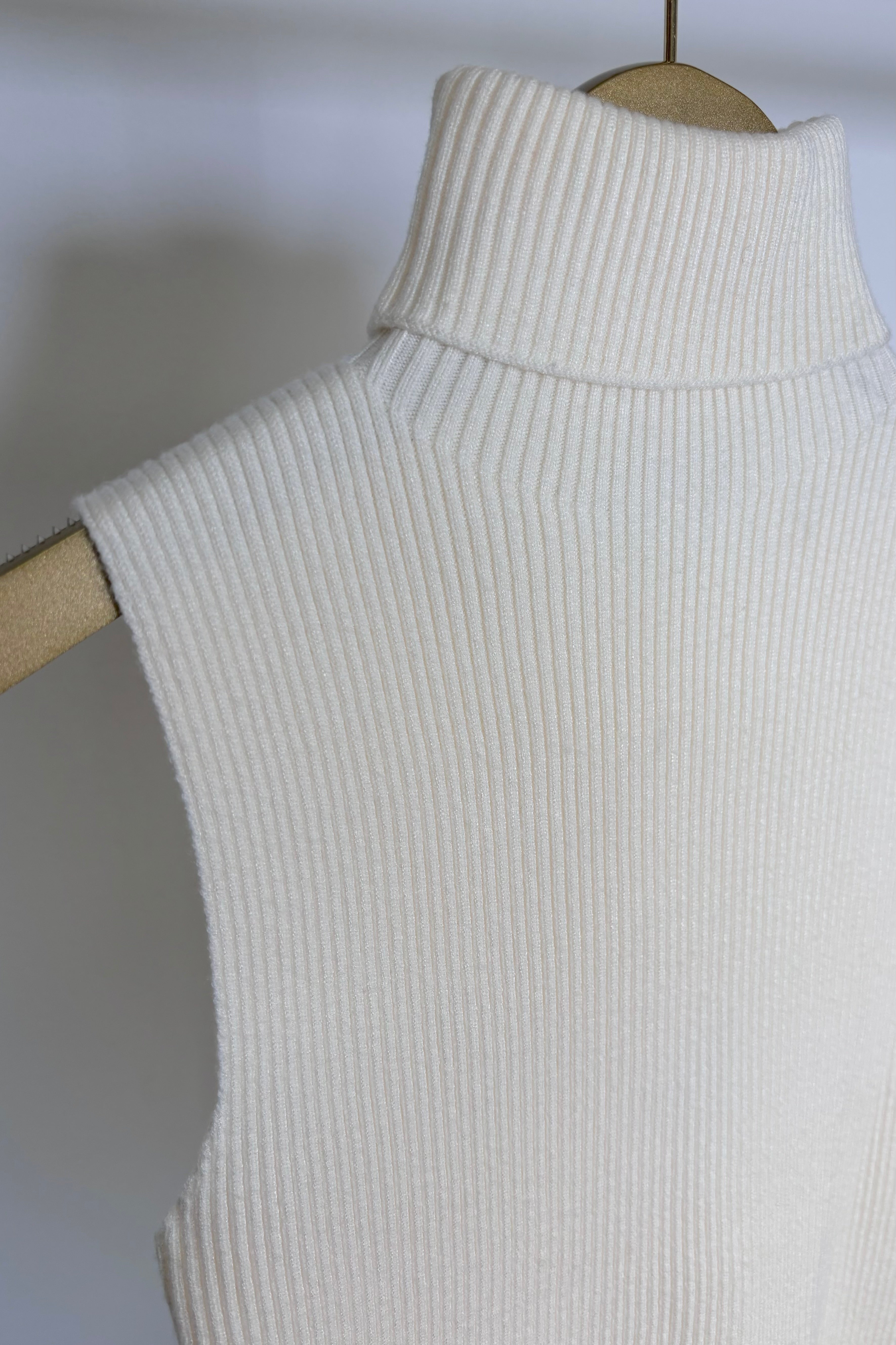 close up of the neck of a cream knitted turtle neck tank top