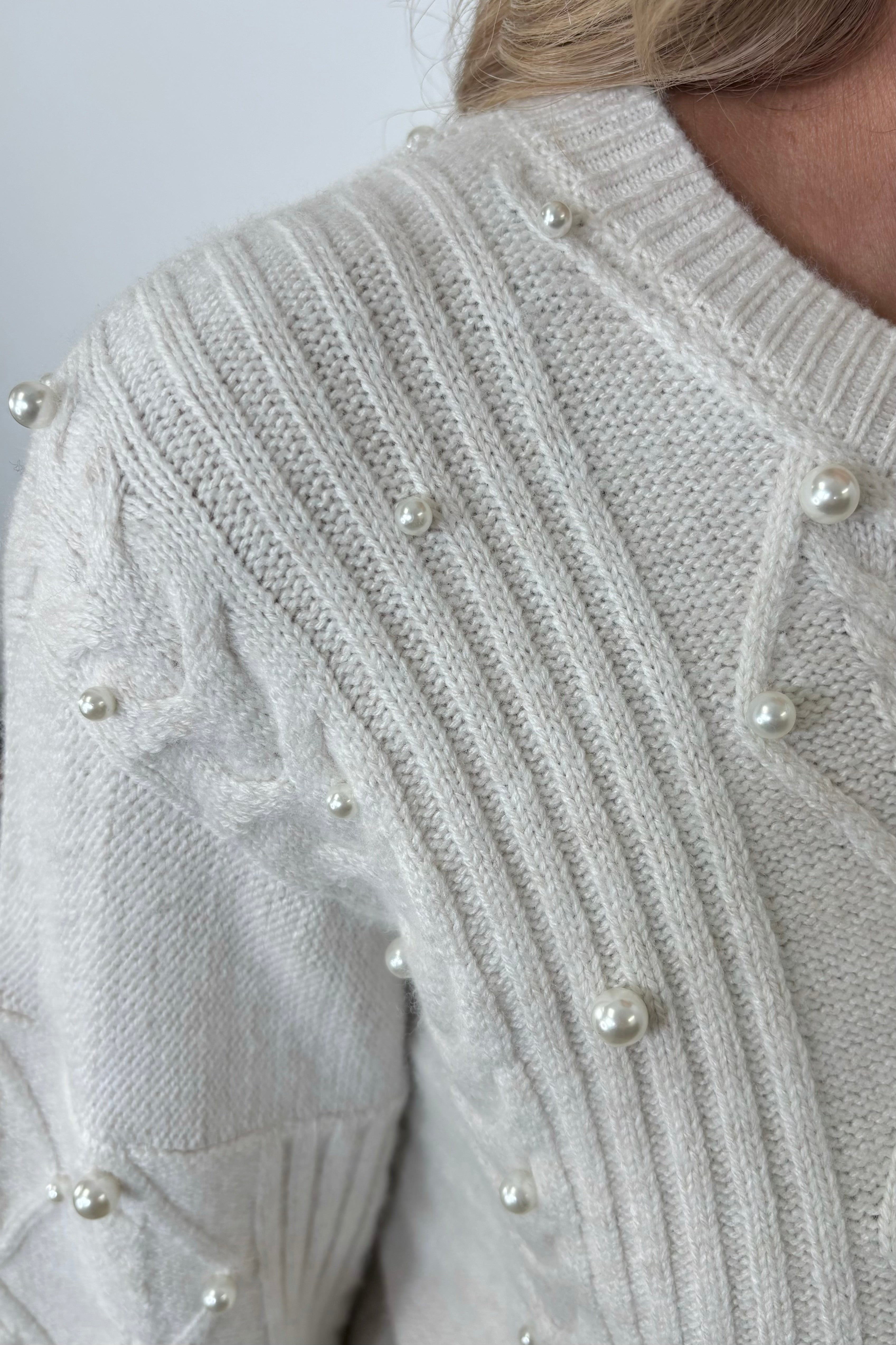 Close-up of a white sweater with pearl embellishments 