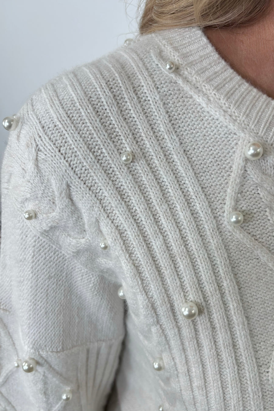 Close-up of a white sweater with pearl embellishments 