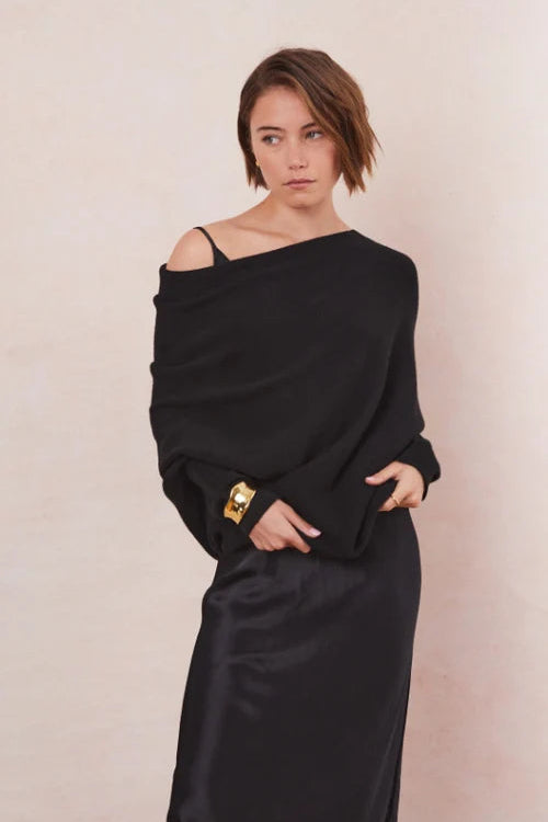 Woman wearing a black off-shoulder sweater on top of a dress 