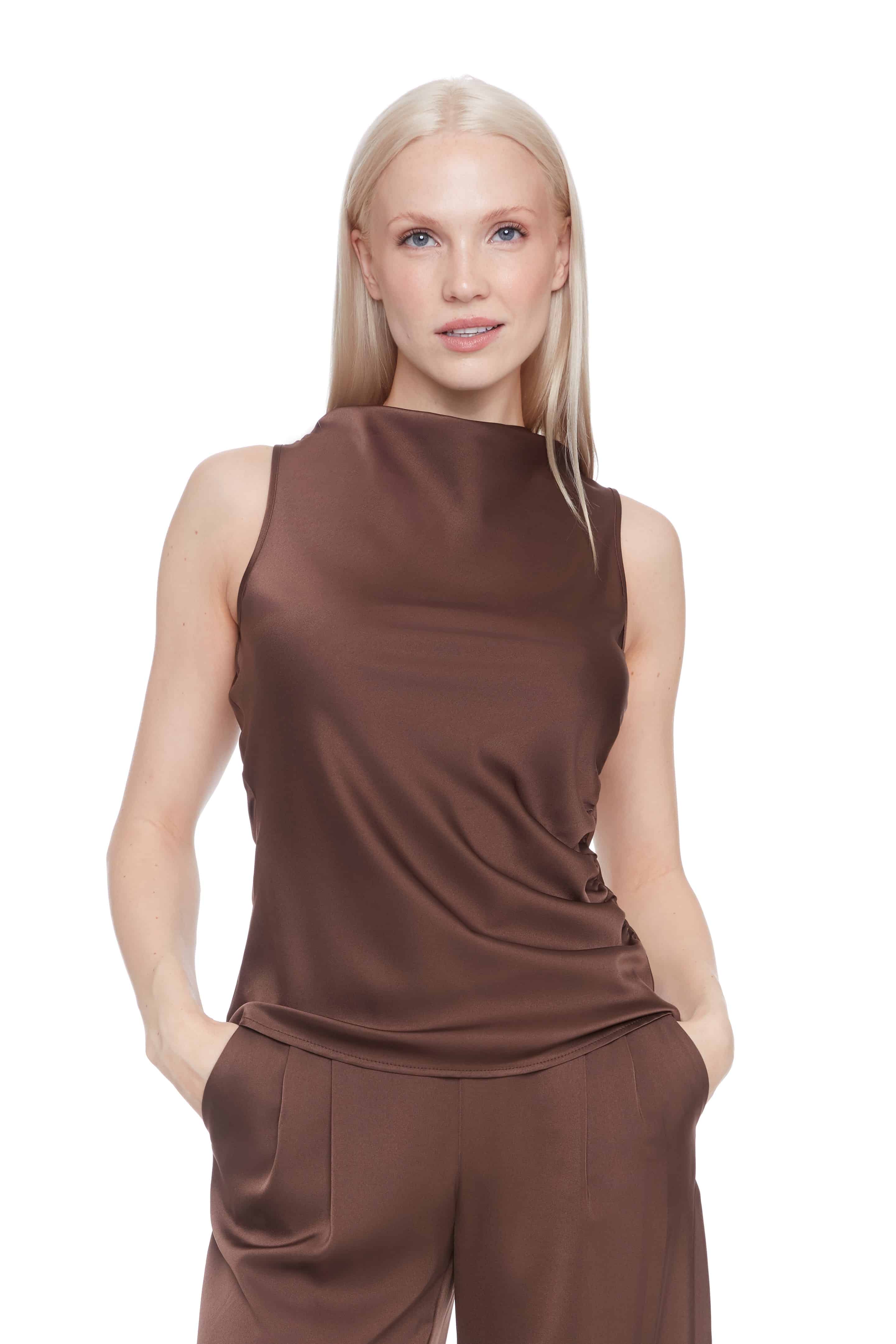 Woman wearing a satin brown sleeveless top and pants on a white background