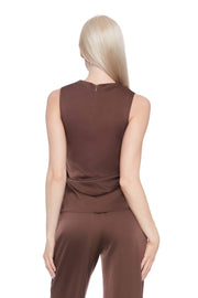 Woman wearing a satin brown sleeveless top and pants on a white 