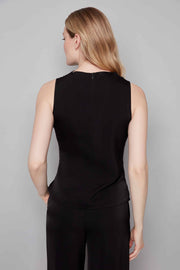 Woman wearing a black sleeveless top and black pants against a gray background