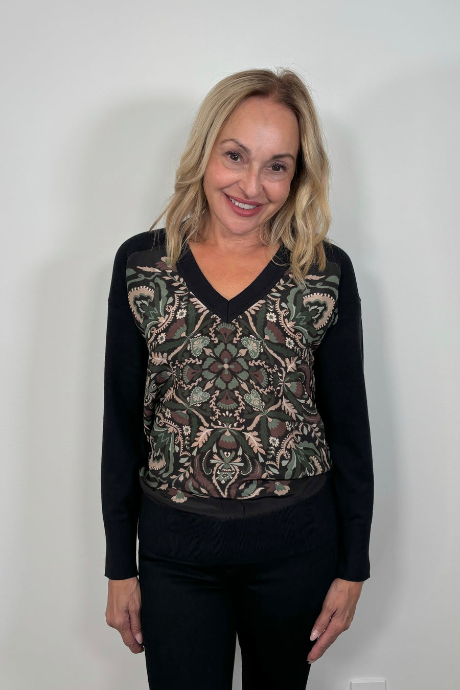 Front view of woman wearing a patterned v-neck black sweater