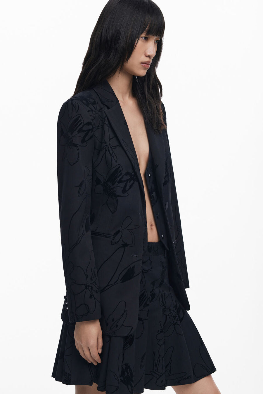 side view of woman wearing a black blazer with textures flowers detailing