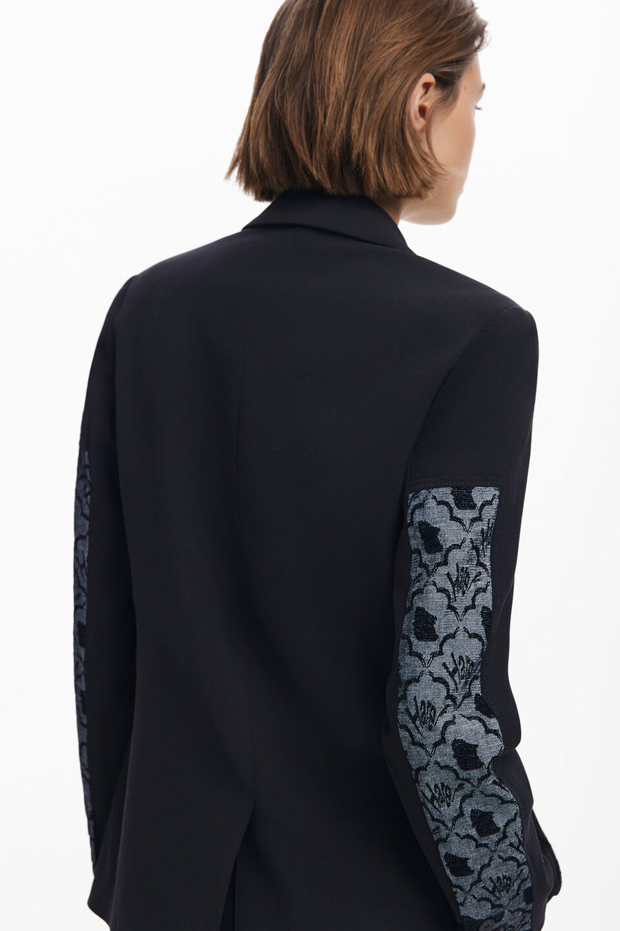 Close-up view of the back of a woman wearing a multi texture blazer