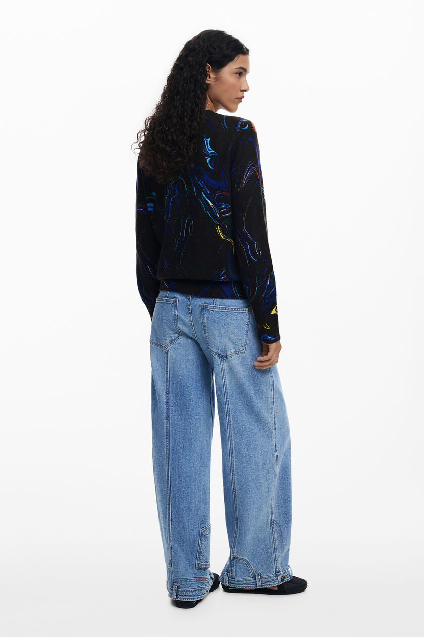 Back view of woman wearing a black long-sleeve sweater with colorful abstract design against a white background