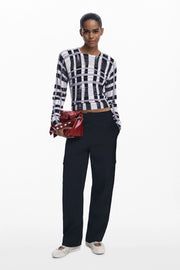 Front full body  view of woman wearing a light-weight plaid black, white and lilac sweater