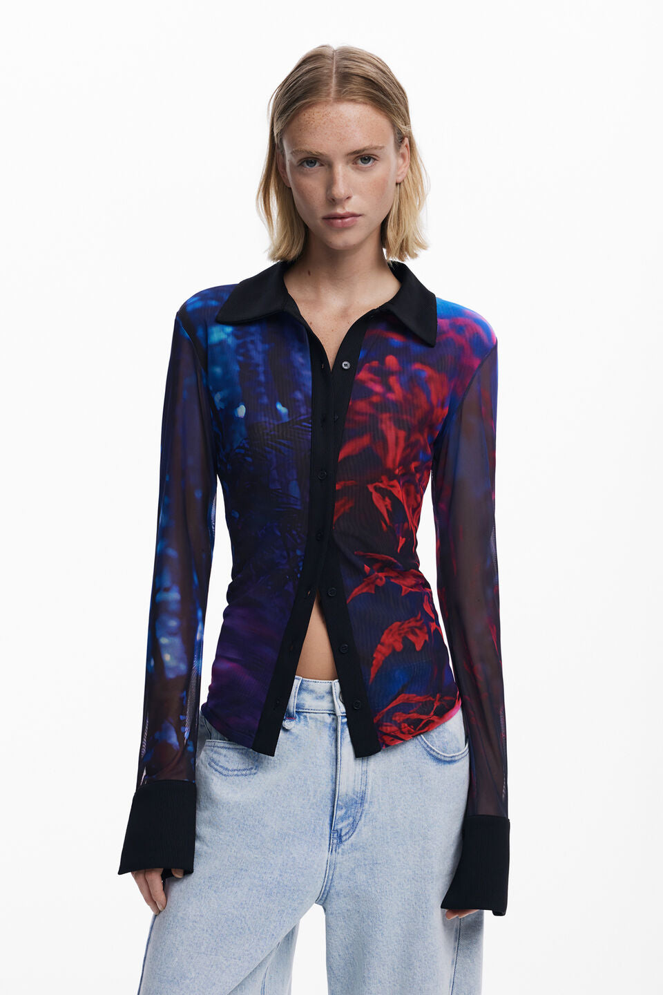 Front view of woman wearing a mesh button down shirt with blue and red patterns.