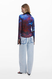 Back view of woman wearing a mesh button down shirt with blue and red patterns.