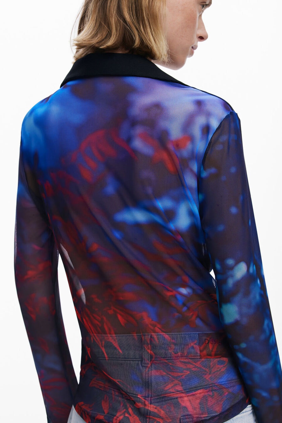 Close-up view of the back of a woman wearing a mesh button down shirt with blue and red patterns.