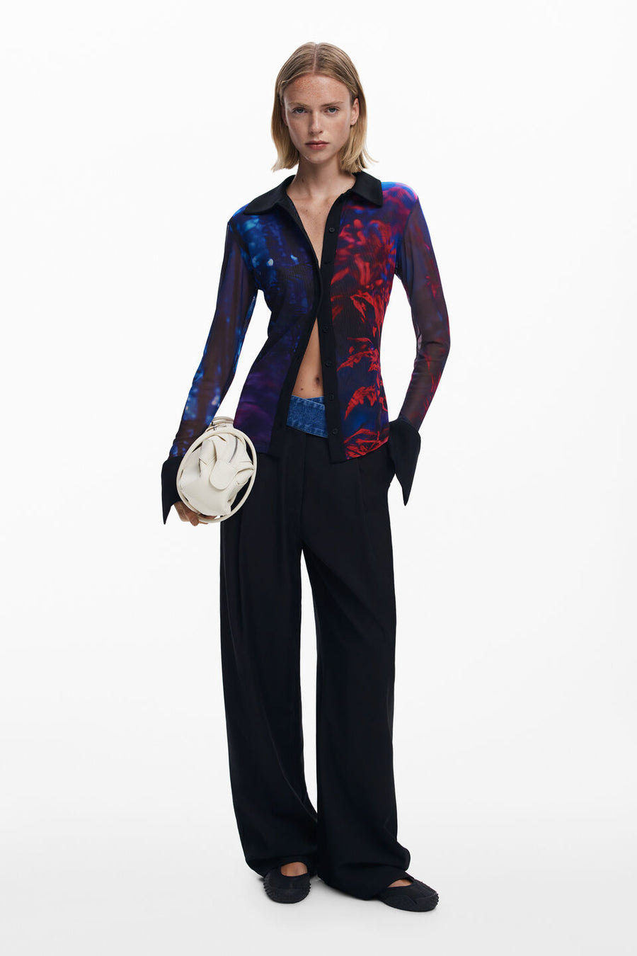 Front full body view of a woman wearing a mesh button down shirt with blue and red patterns.
