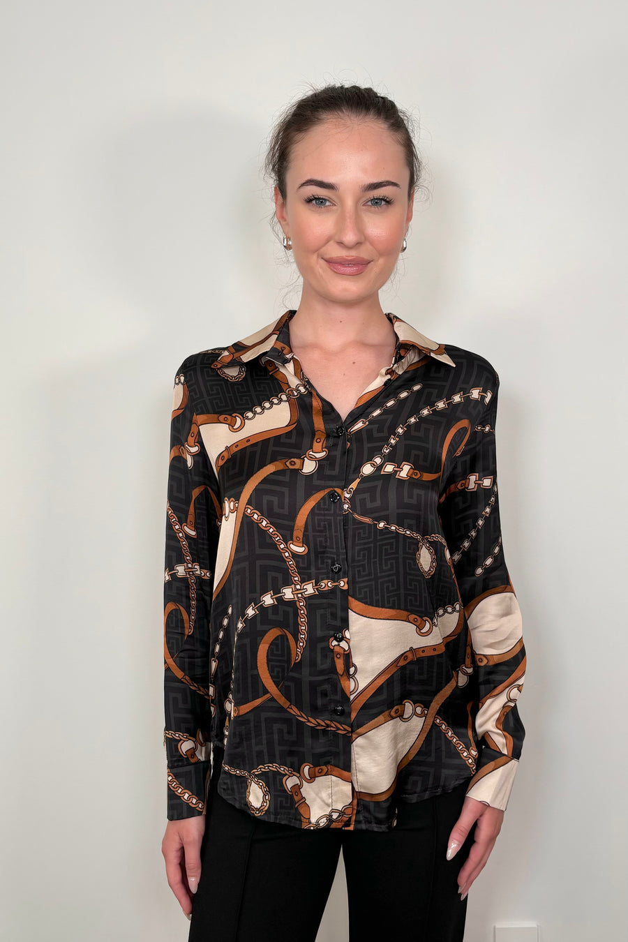 Front view of a woman wearing a printed button up shirt untucked