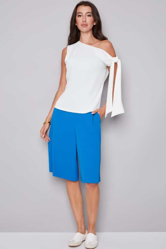 woman wearing a white one-shoulder top with a draped tie sleeve detail, front