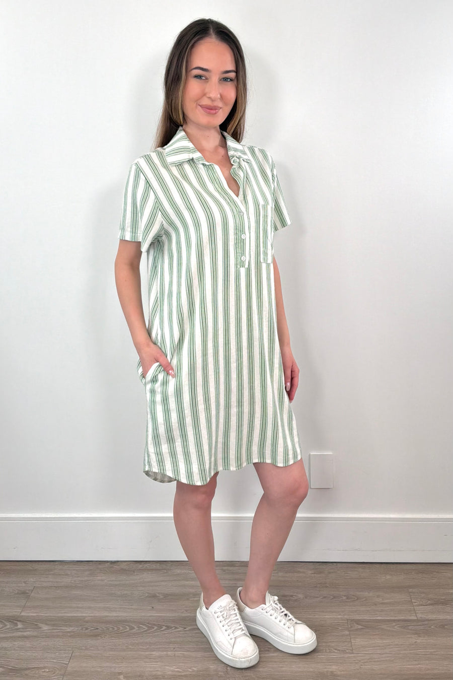 Side view of a woman wearing a light green and white striped shirt dress with collar