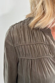 Woman wearing an olive green button up blouse 
