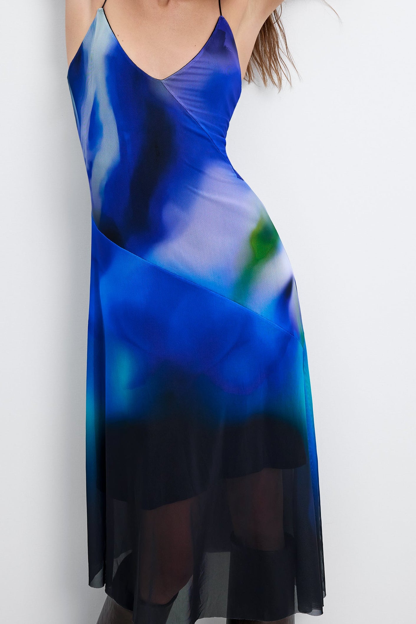 blue watercolor midi slip dress featuring a v-neckline, spaghetti straps, and a sheer mesh asymmetrical hem