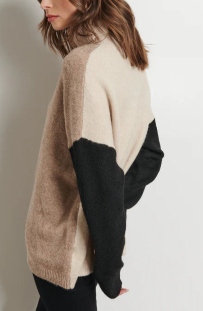 Woman wearing a color-blocked sweater against a plain background