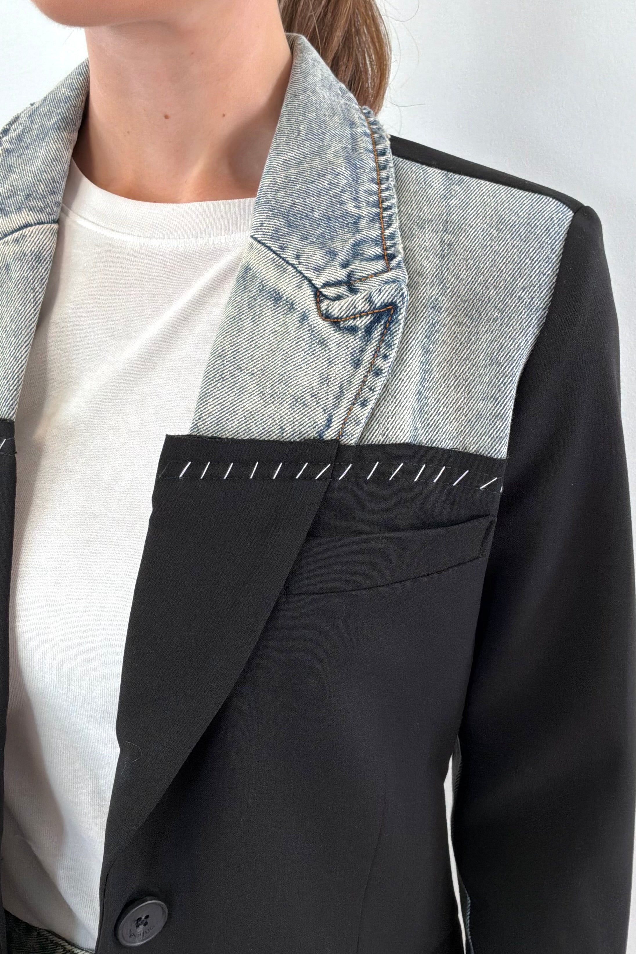 Close of Woman wearing a mixed denim fabric blazer in black and hints of light blue