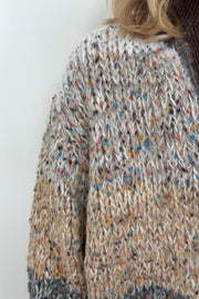 Close up of woman wearing a light gray, beige and dark gray knitted cardigan