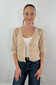 A woman wearing a unbuttoned pointelle knit cardigan in latte