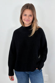 Woman wearing a black sweater with green heart patches