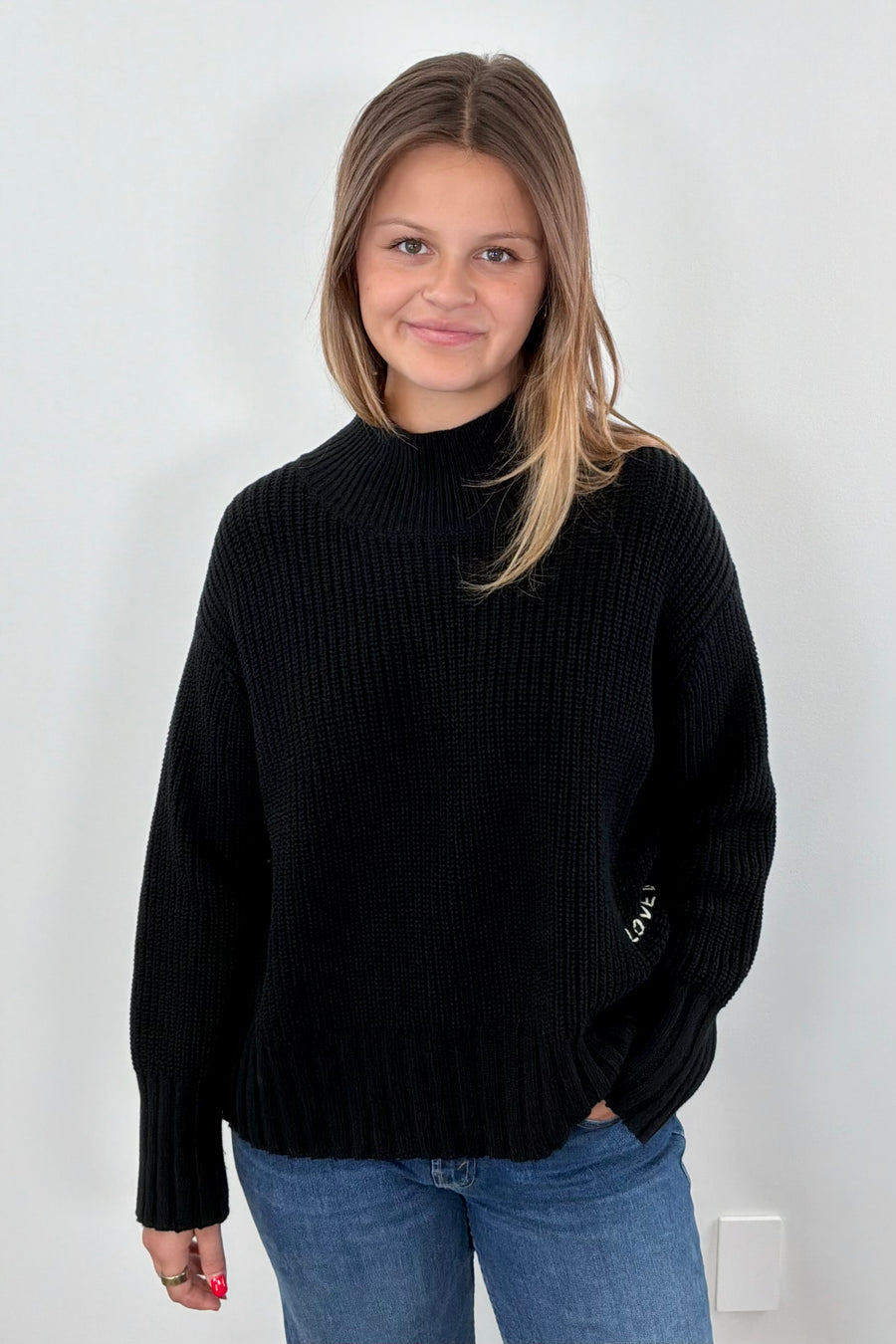 Woman wearing a black sweater with green heart patches