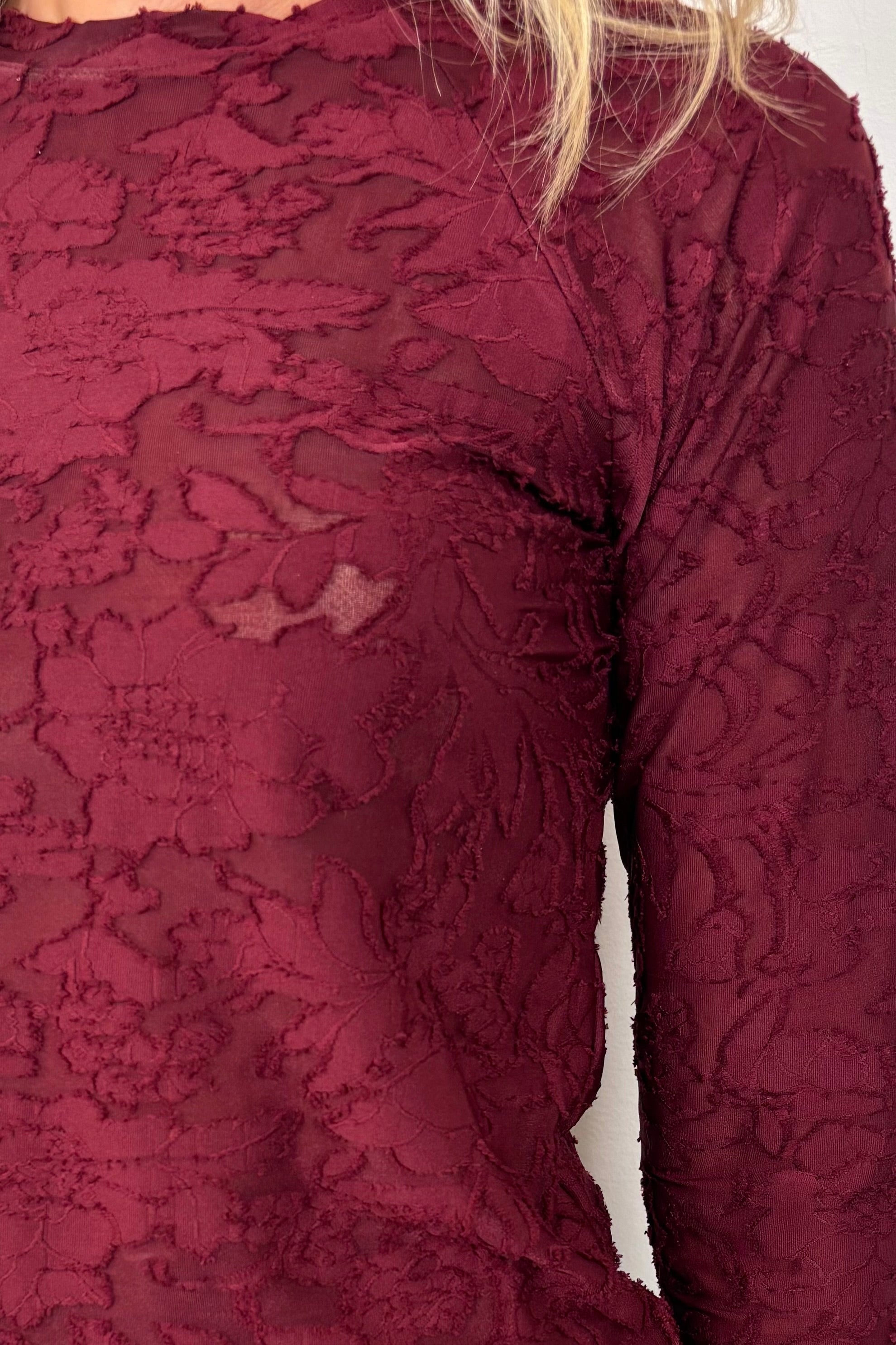 Close-up of a woman wearing a long sleeve burn out floral tee