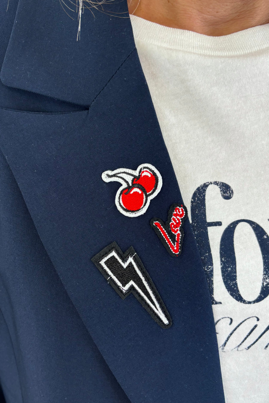 Close up of Woman wearing a navy blue blazer with gold buttons and patch details