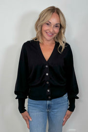 front facing woman wearing a black cotton, silk and cashmere blend cardigan with extended cuffs closed.